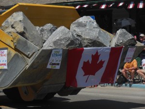Front end loader with actual rocks moved by the floodwaters.