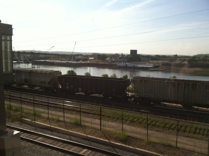 View of trains and barges on the Mississippi RIver at St. Paul from Union Depot platform.